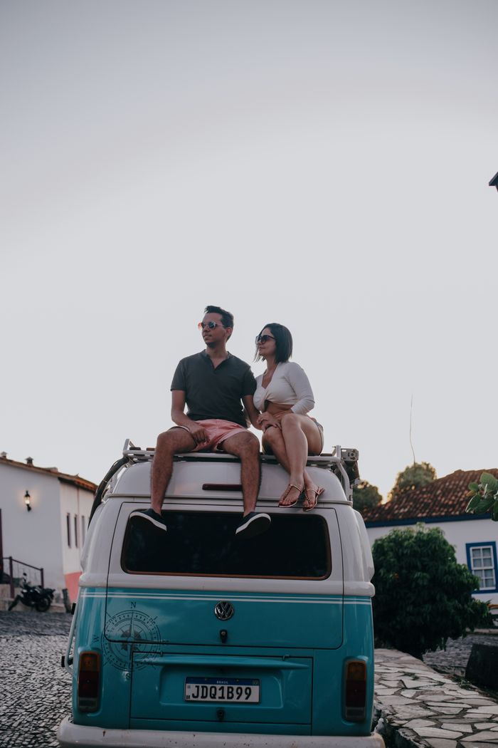 menu-13 Couple sitting on a vintage van roof, enjoying a sunset with a relaxed vibe.