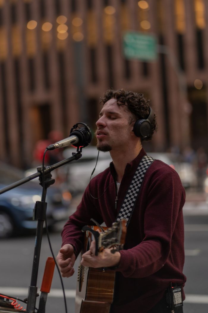 menu-04 Musician performing live with guitar and microphone on an urban street.