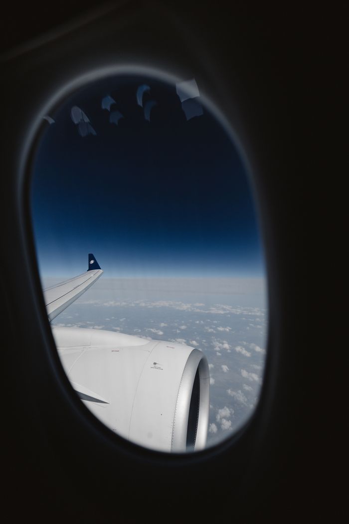 menu-16 Scenic aerial view from airplane window showing sky and clouds with wing in focus.