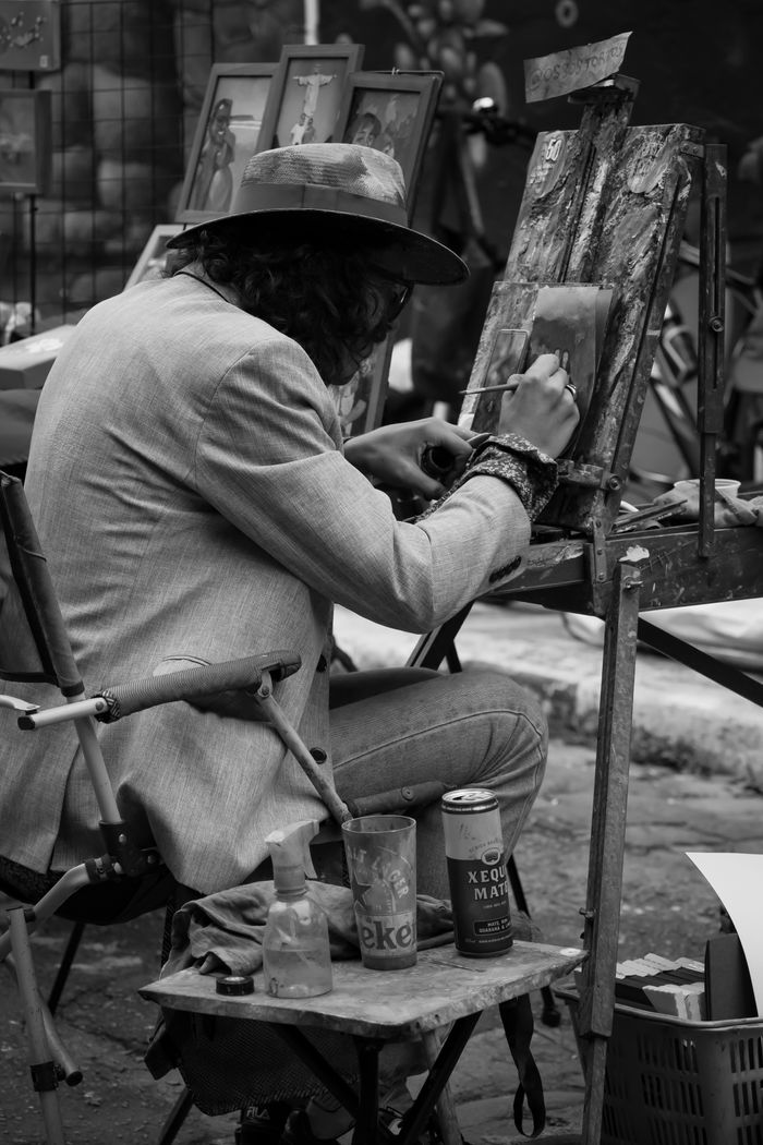 menu-07 Black and white street photography of an artist painting outdoors, showcasing creativity.
