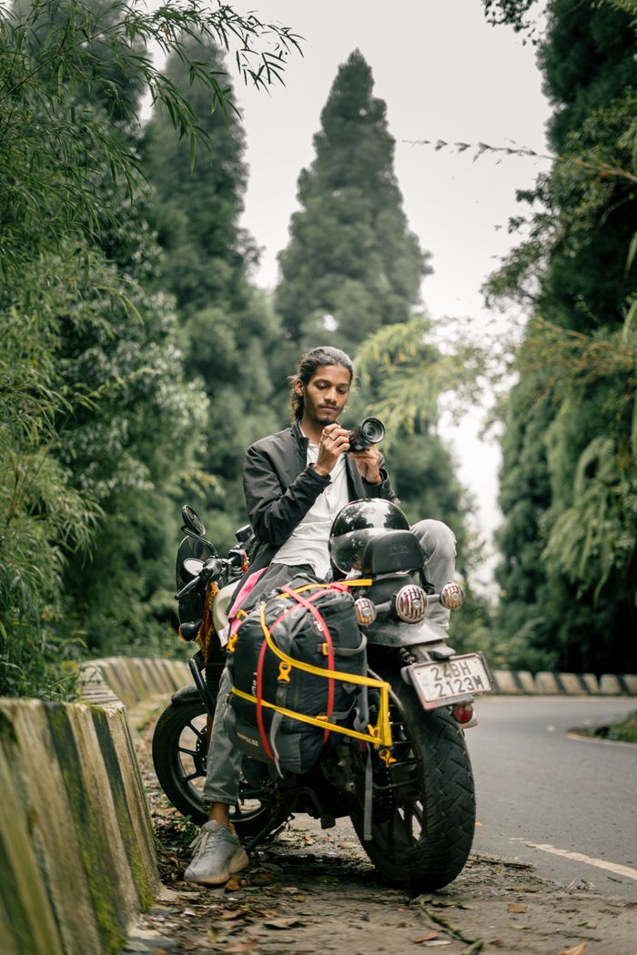 about-01 Young traveler on a motorcycle enjoying the lush greenery of Darjeeling's forests.