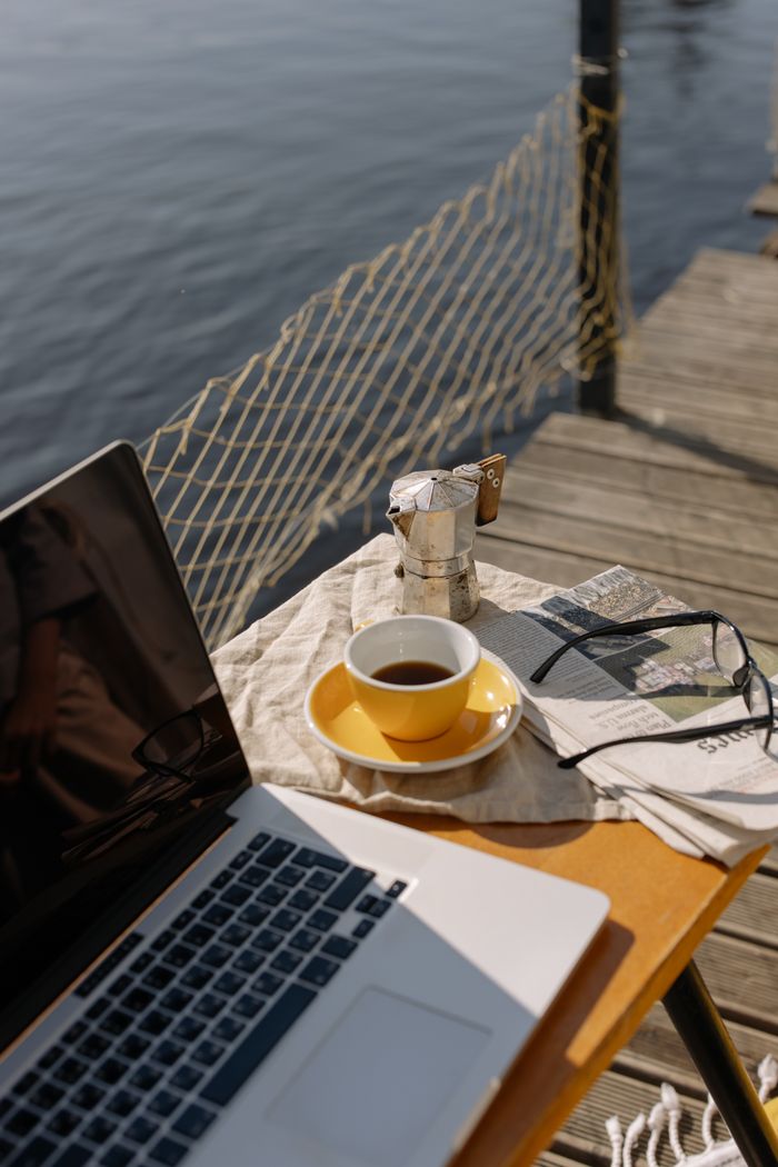 menu-11 Relaxing outdoor workspace setup by the lake with coffee and laptop, perfect for inspiration.